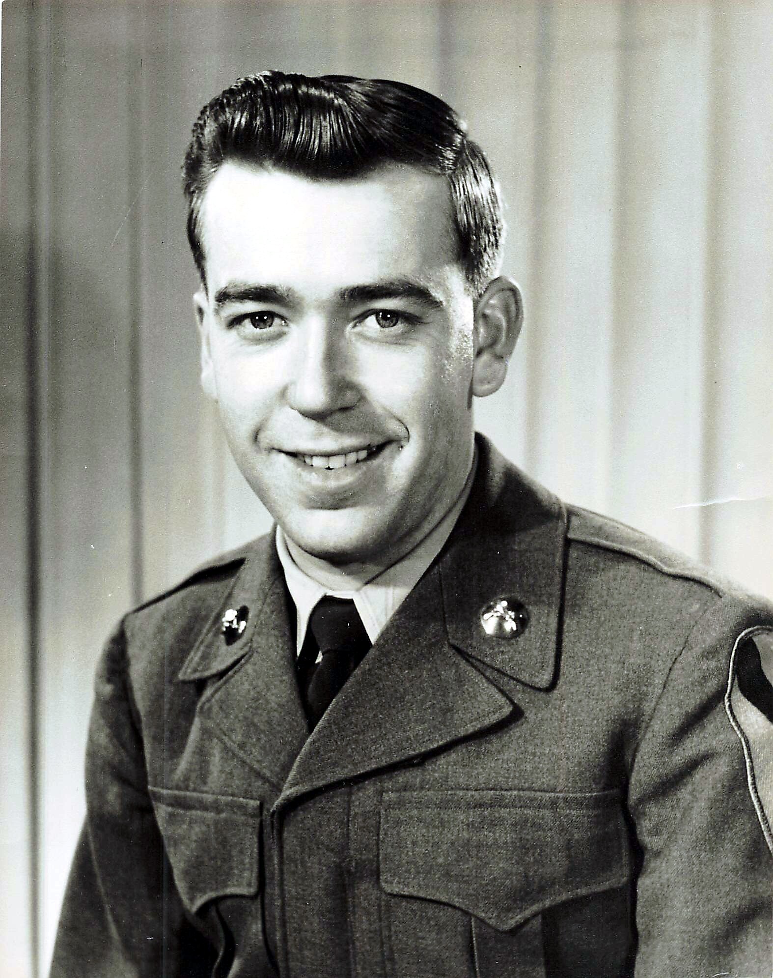 Young man in a vintage military uniform smiling for a portrait.