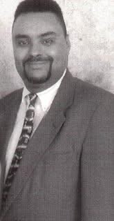 Portrait of a man in a suit and tie, smiling at the camera.