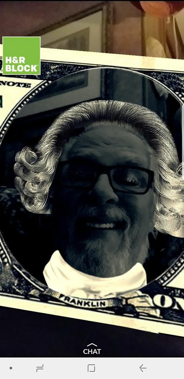 Selfie of a man with a white powdered-wig filter inside a dollar-bill frame and the H&R Block logo in the corner, smiling.