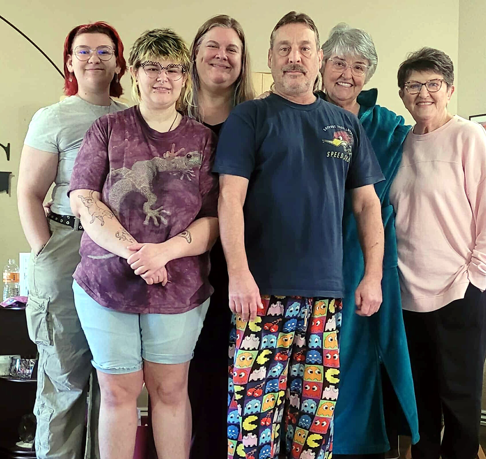 Six adults standing together indoors, smiling at the camera.