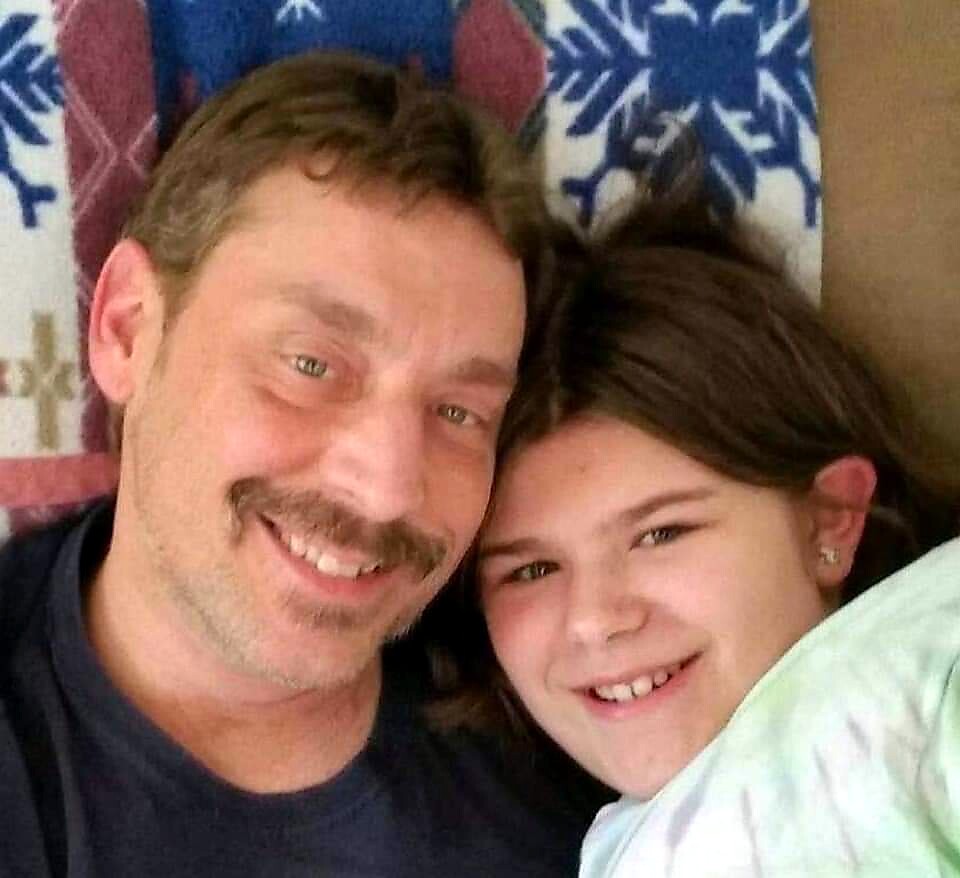 Smiling man and girl posing for a selfie indoors, close together.