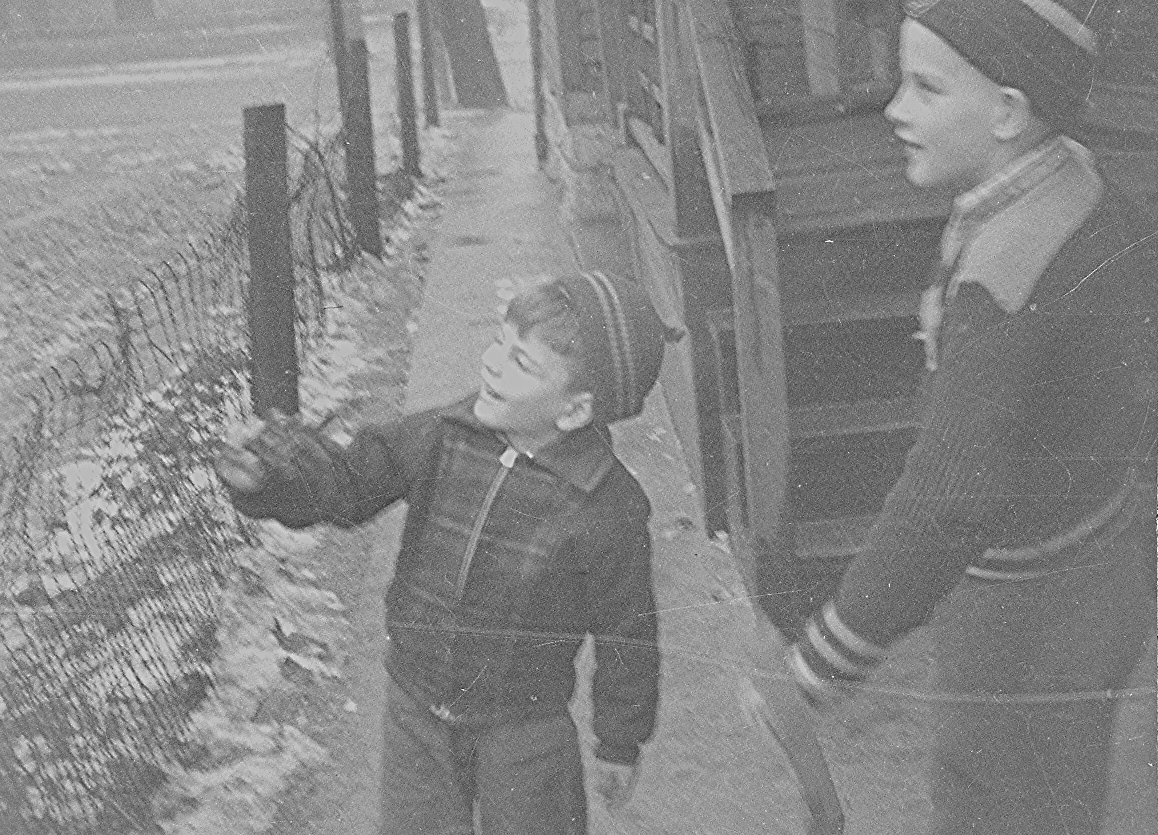 Old black-and-white photo of a child and an adult in coats, looking out of a bus or tram window and smiling.