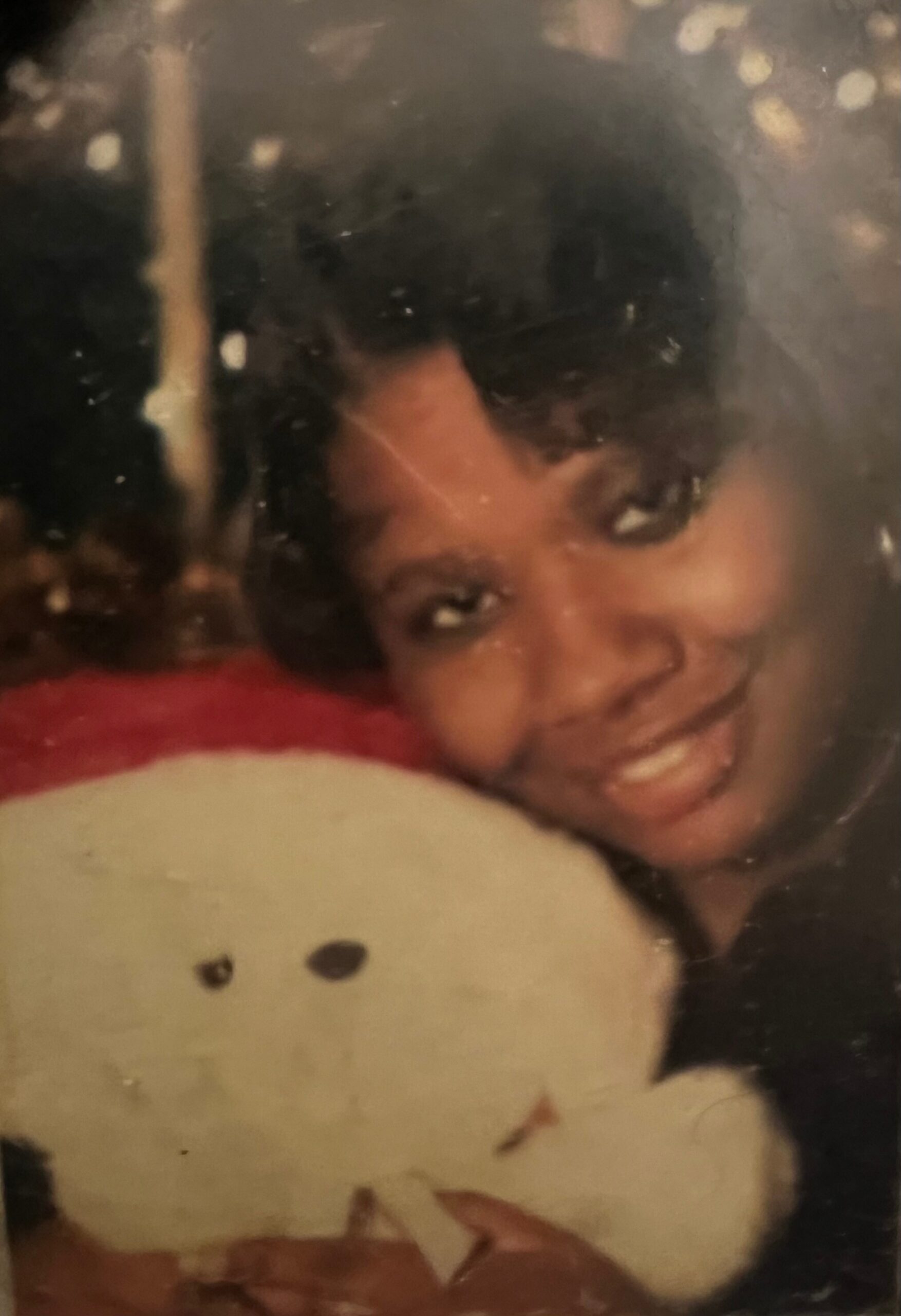 Person with dark hair smiling at the camera, leaning on a white pillow with black spots.