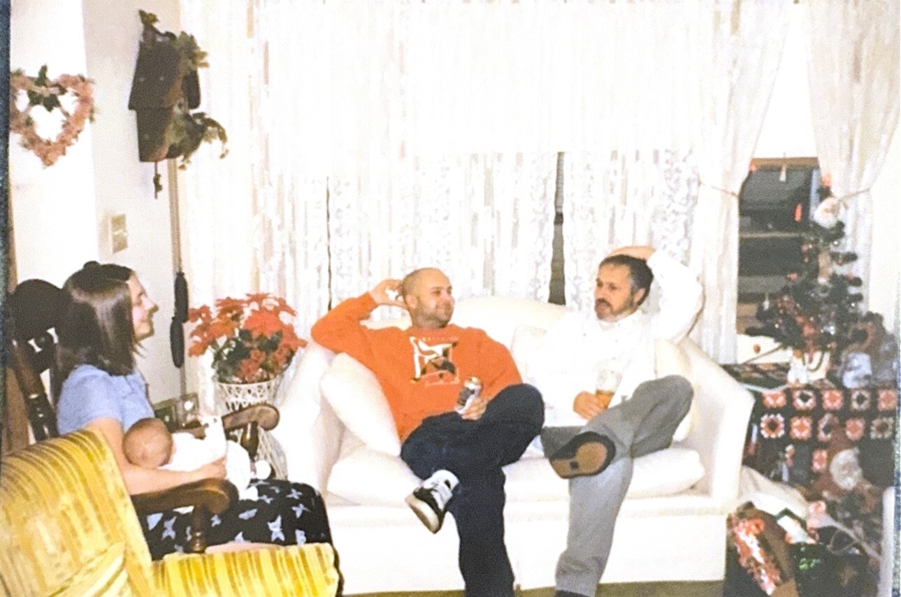 People relaxing in a cozy living room during a casual gathering, a baby on a woman’s lap and gifts on the side on a cozy couch party setup.