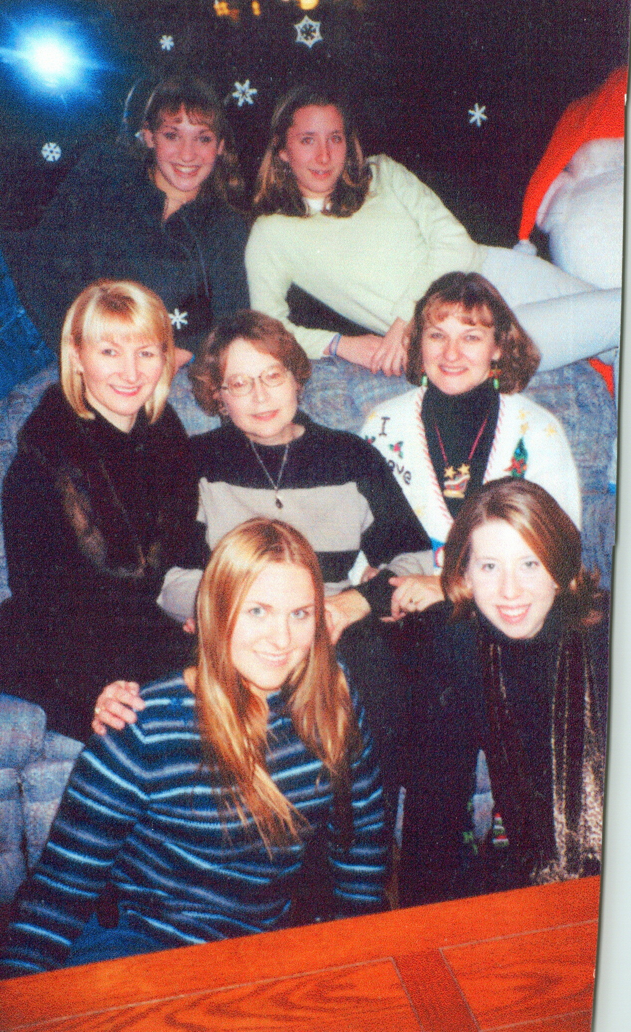 Group of smiling people posing together indoors at a festive gathering (likely Christmas).