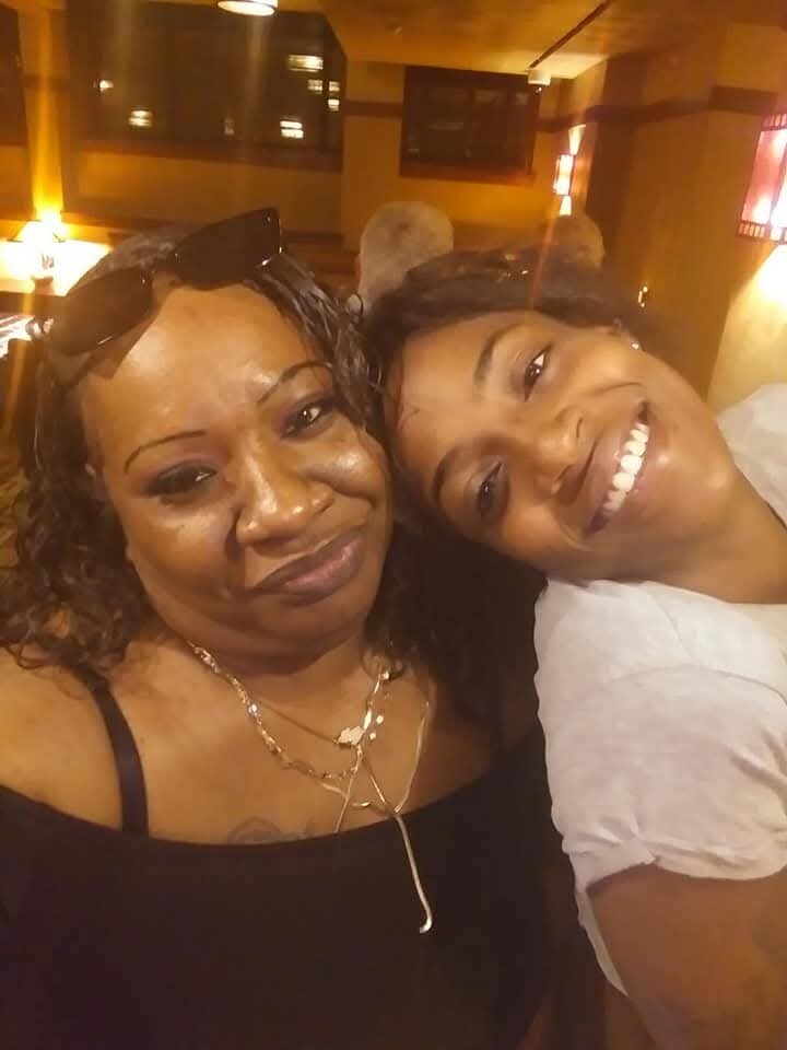 Two women smiling and posing for a selfie in a warm, indoor setting.