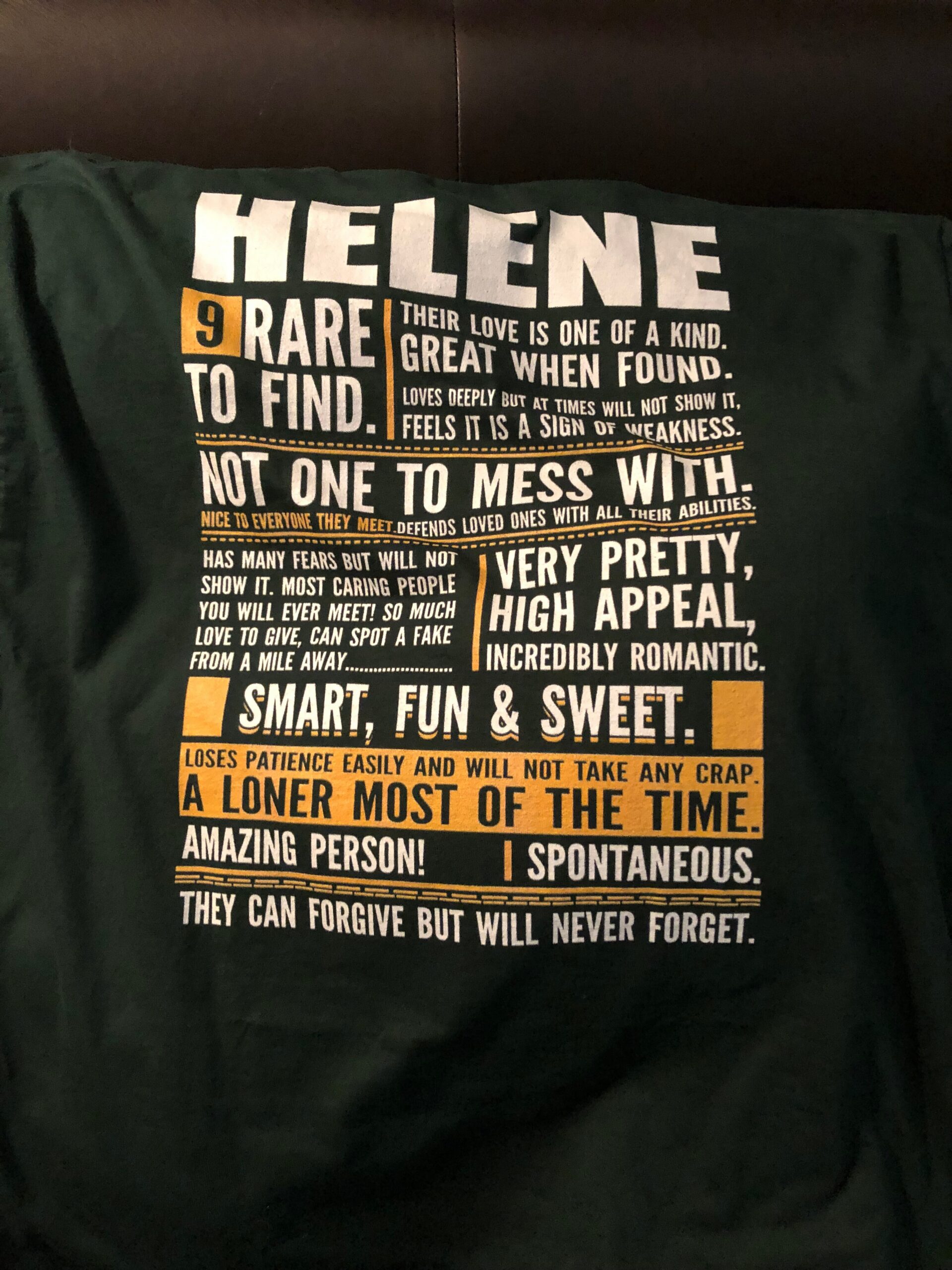 Black T-shirt with large white and orange typographic design featuring the name 'HELENe' and blocks of quoted text across the front.