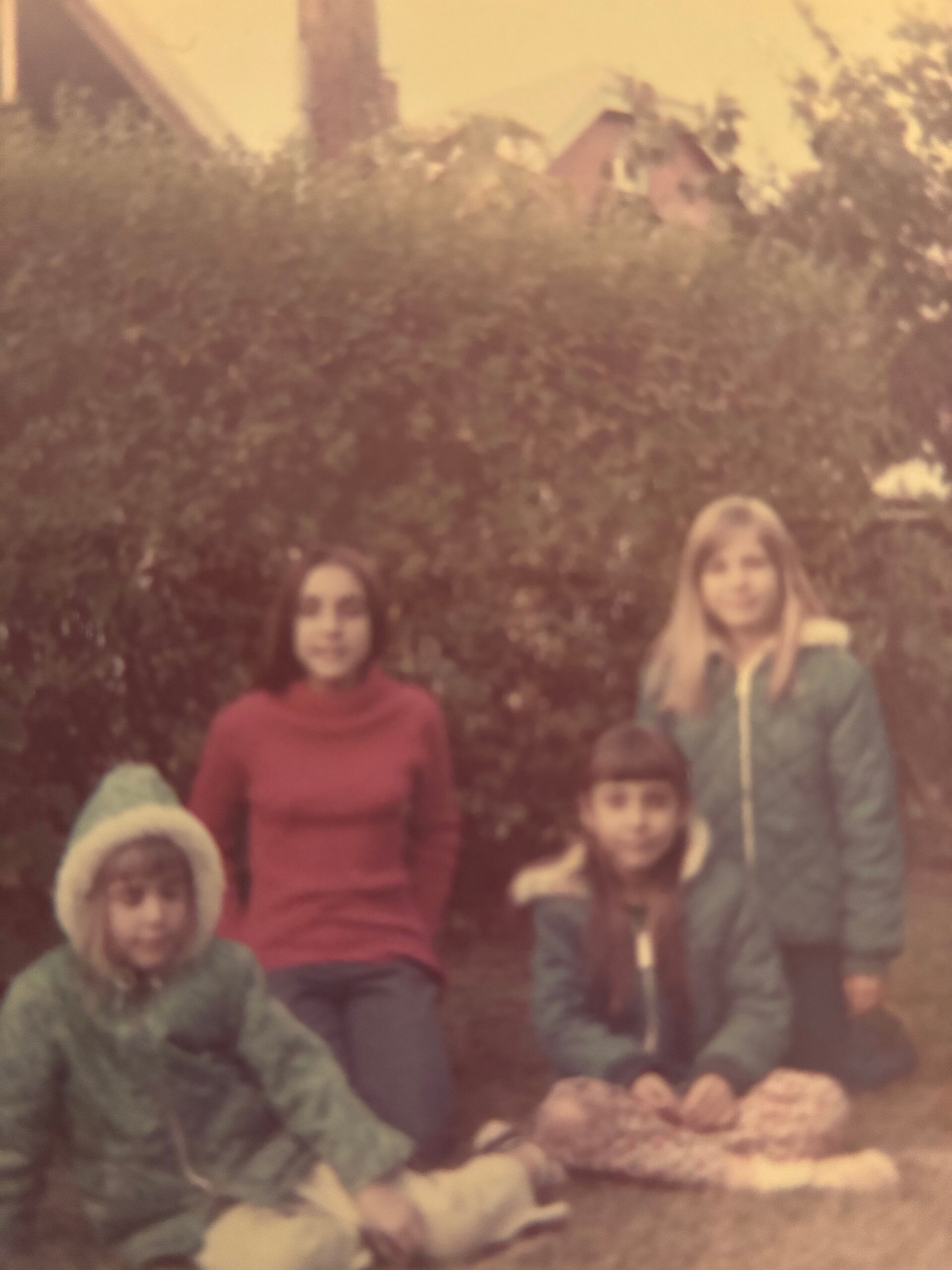Blurry vintage photo of several children in winter coats posing outdoors, with muted colors and a snowy or frosty background.