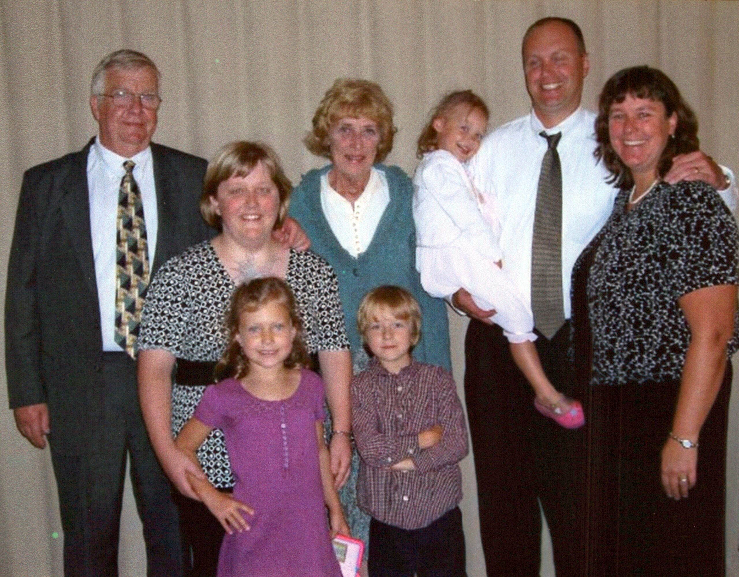 Family group posing for a photo indoors, adults and children smiling at the camera.