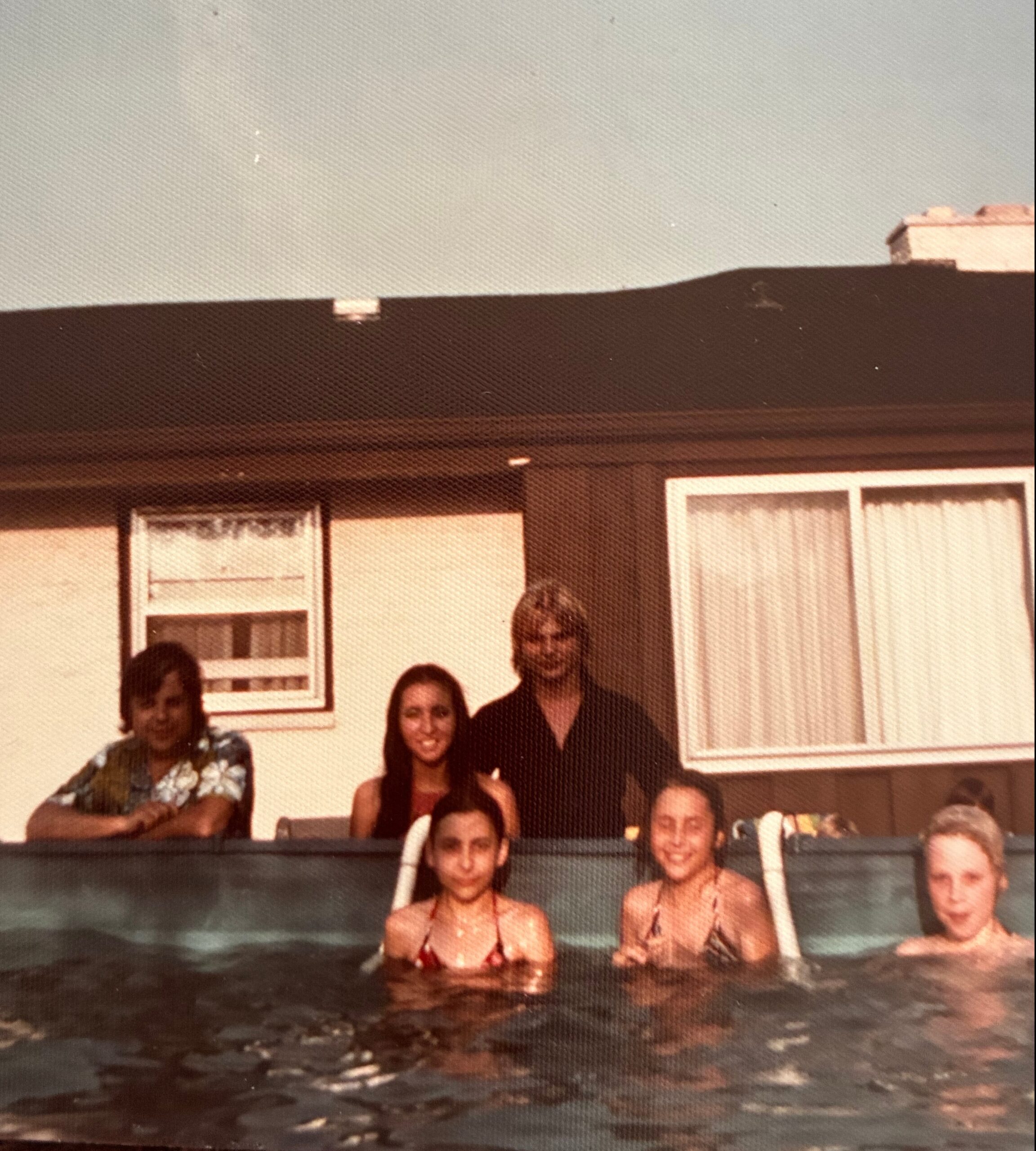 Group of people posing for a photo in a pool area, with posters on the wall behind them.