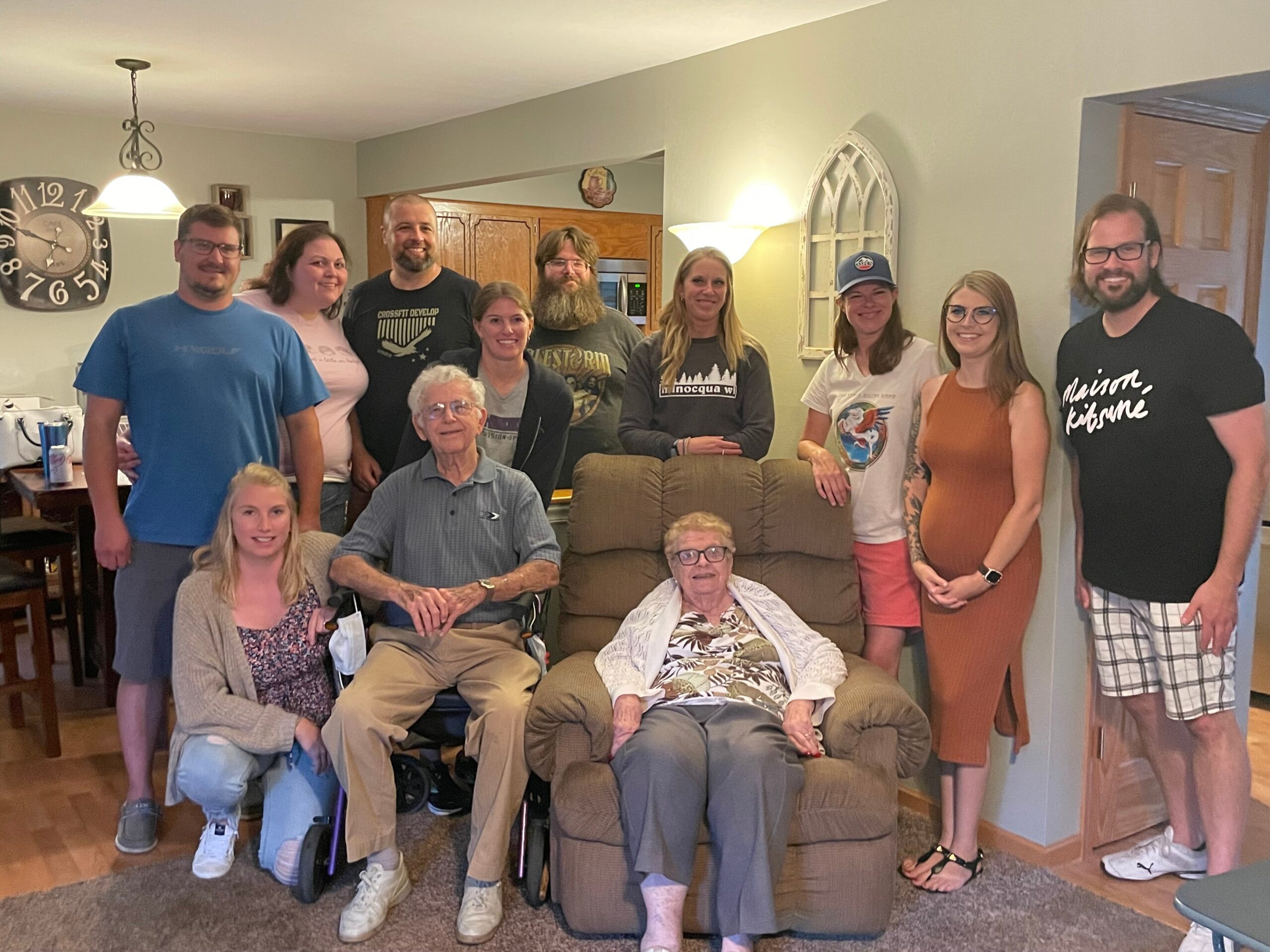 Group of adults and seniors posing together in a cozy living room for a group photo, smiling at the camera.