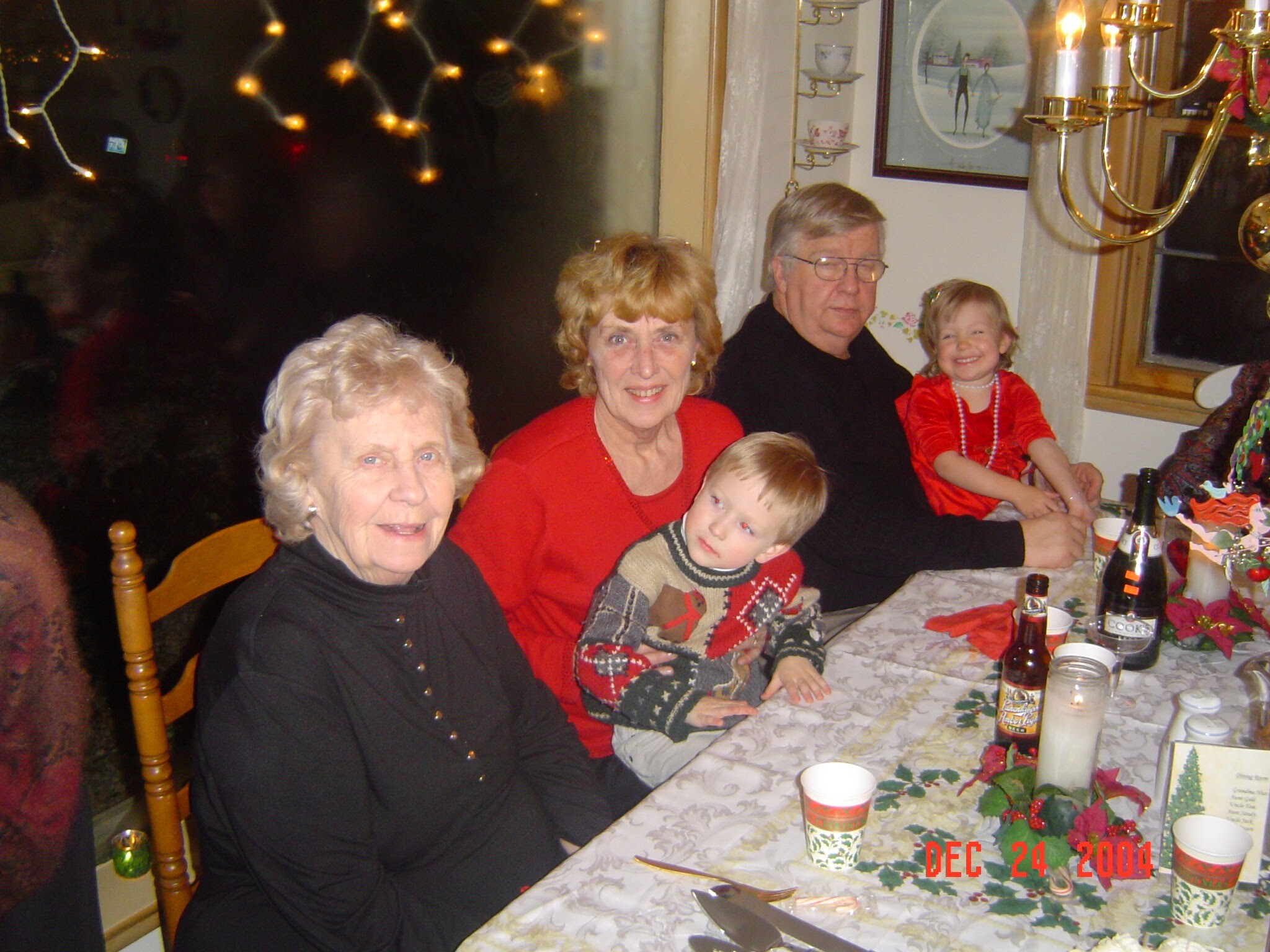 Group of family members at a festive dinner, seated around a table with candles and holiday decor classic for Christmas.