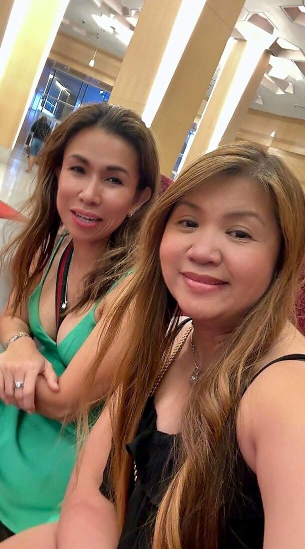 Two women take a selfie in a bright hotel lobby, smiling at the camera.