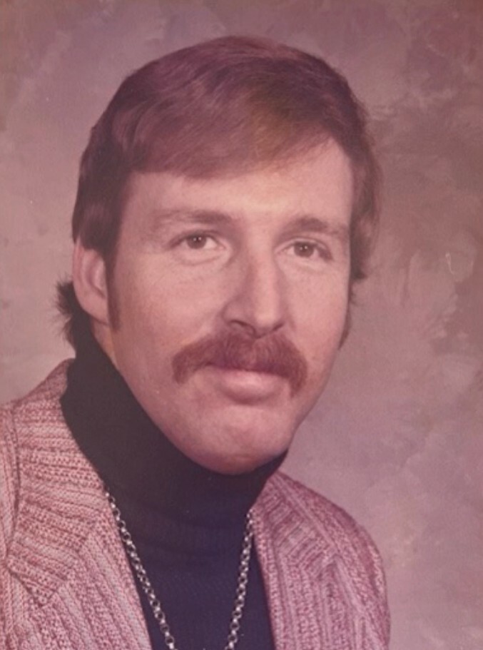 Portrait of a man with a thick mustache wearing a black turtleneck and pink plaid jacket, studio backdrop, 1970s style