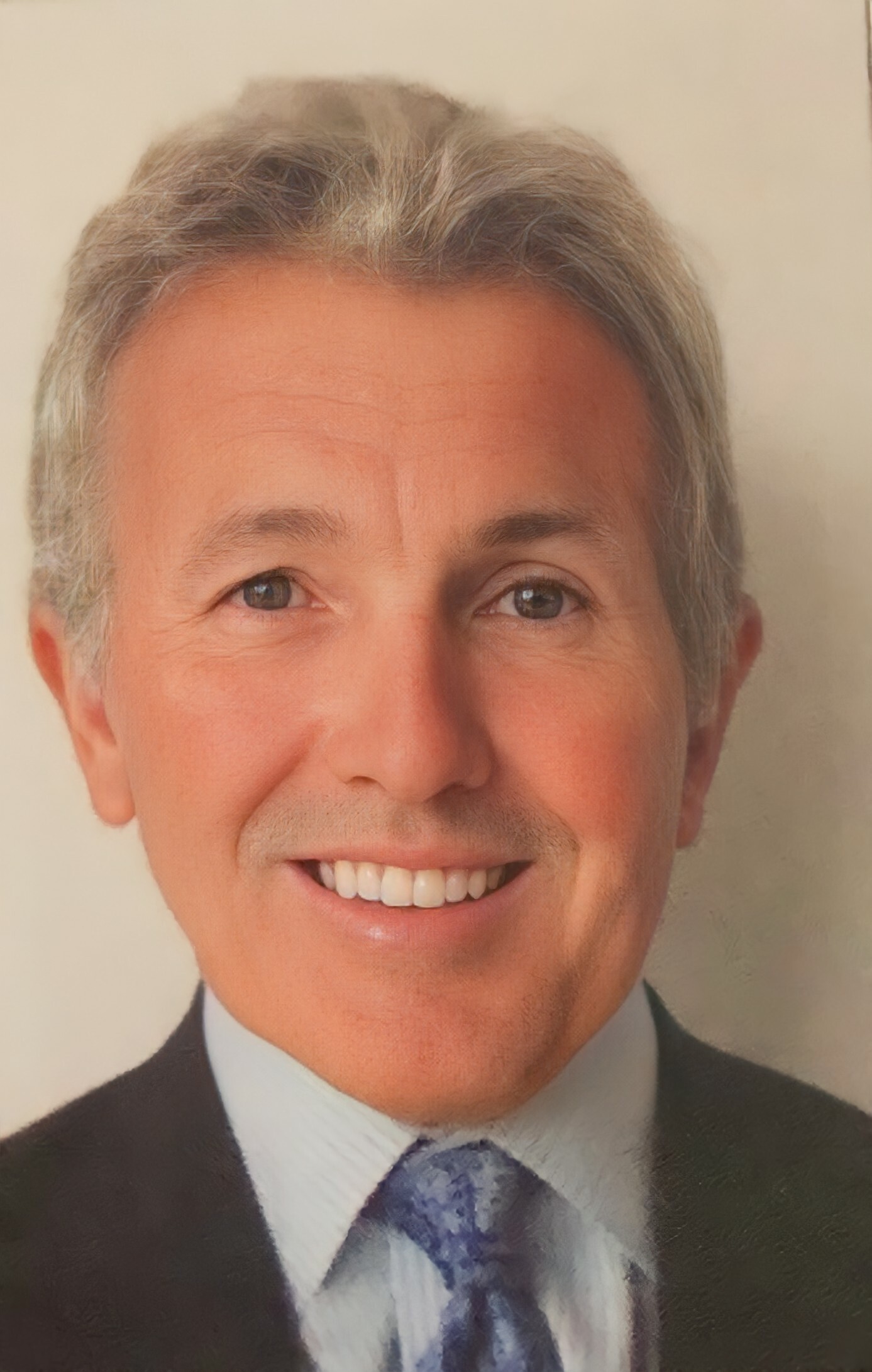 Smiling man in a dark suit and blue patterned tie, close-up portrait.