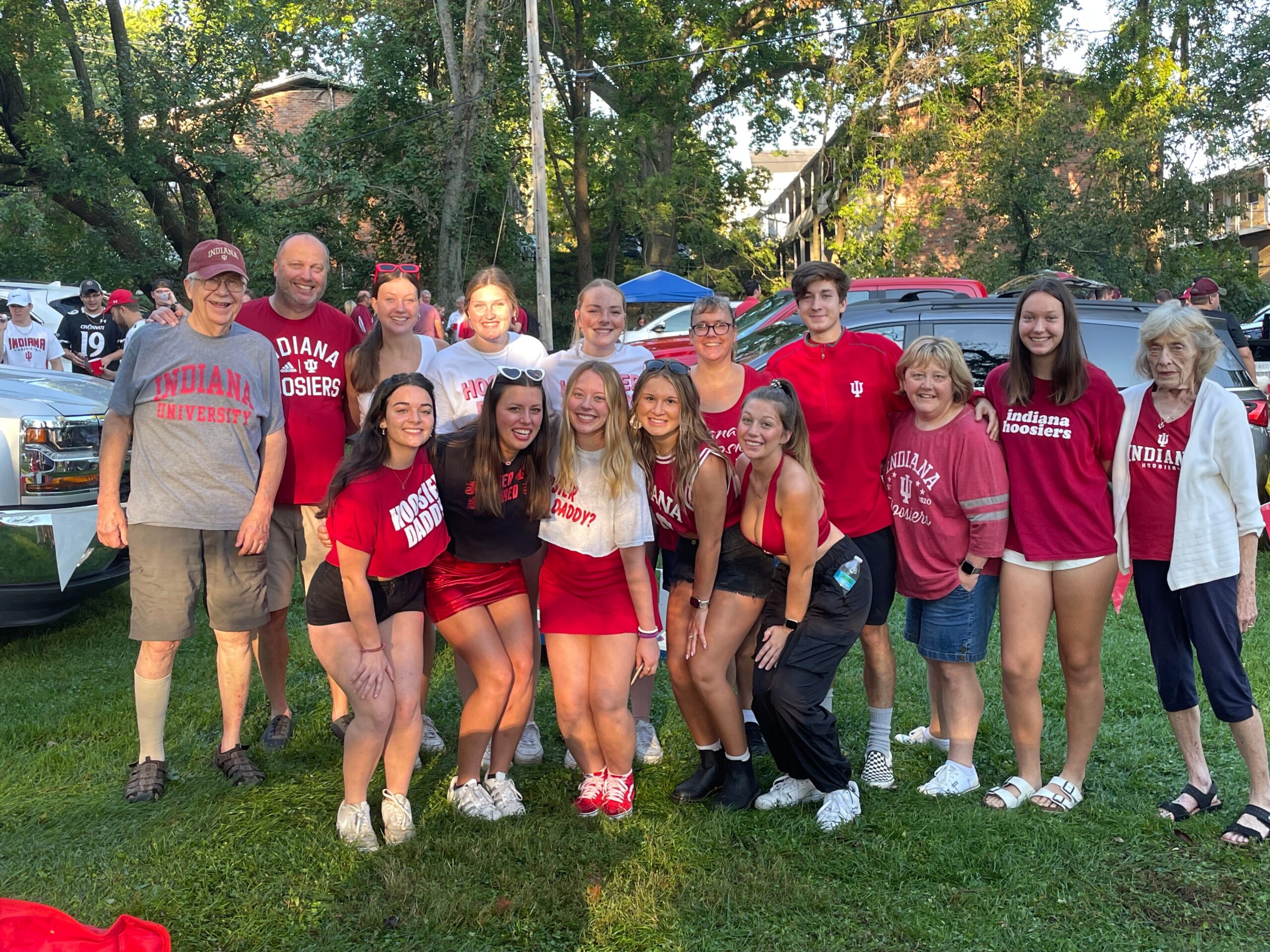 Group of Indiana University fans posing together outdoors, many wearing red shirts and smiles.