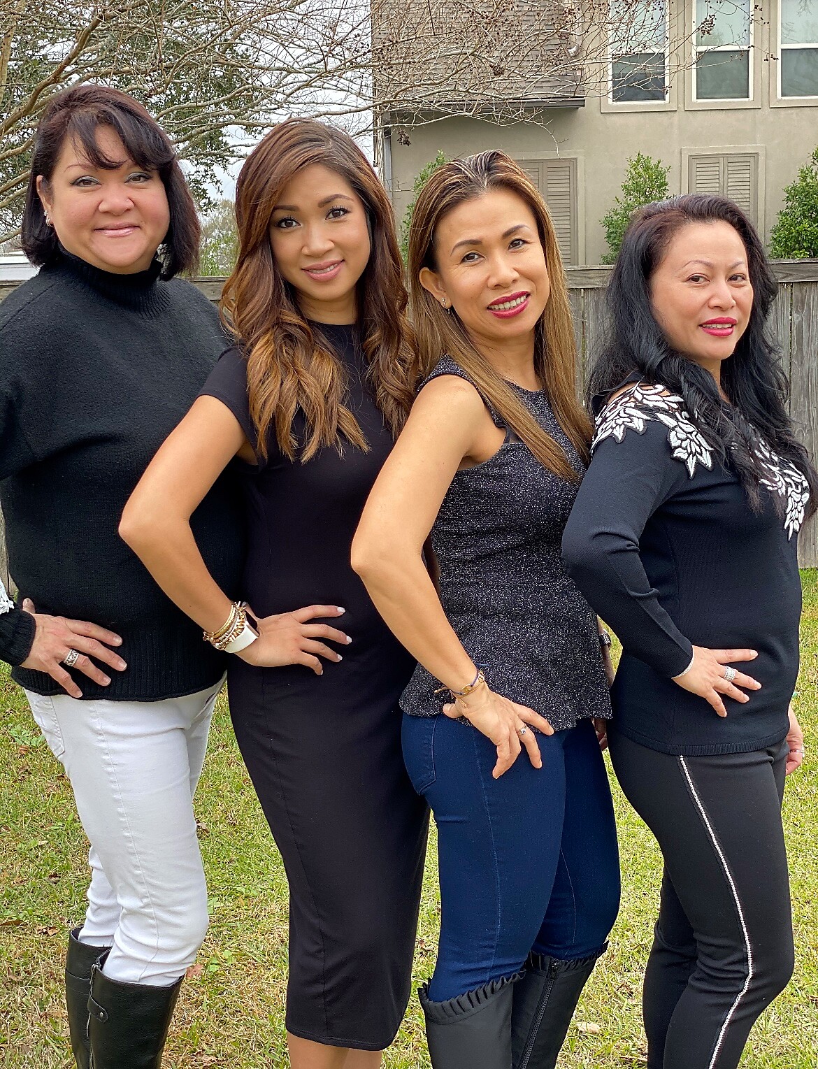Four women standing in a row outdoors with hands on hips, smiling at the camera.