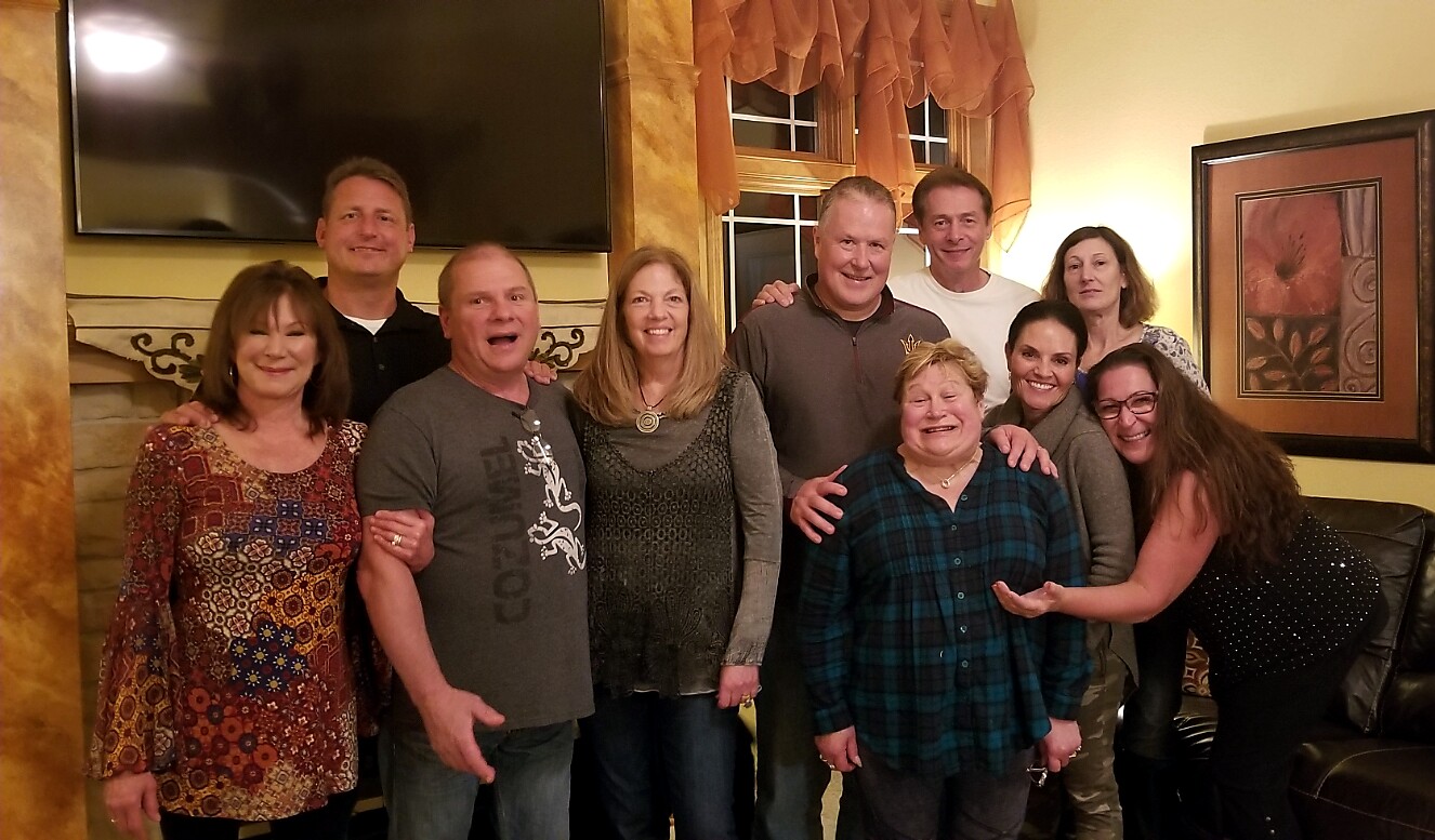 A group of adults posing together in a cozy living room, smiling for the photo.