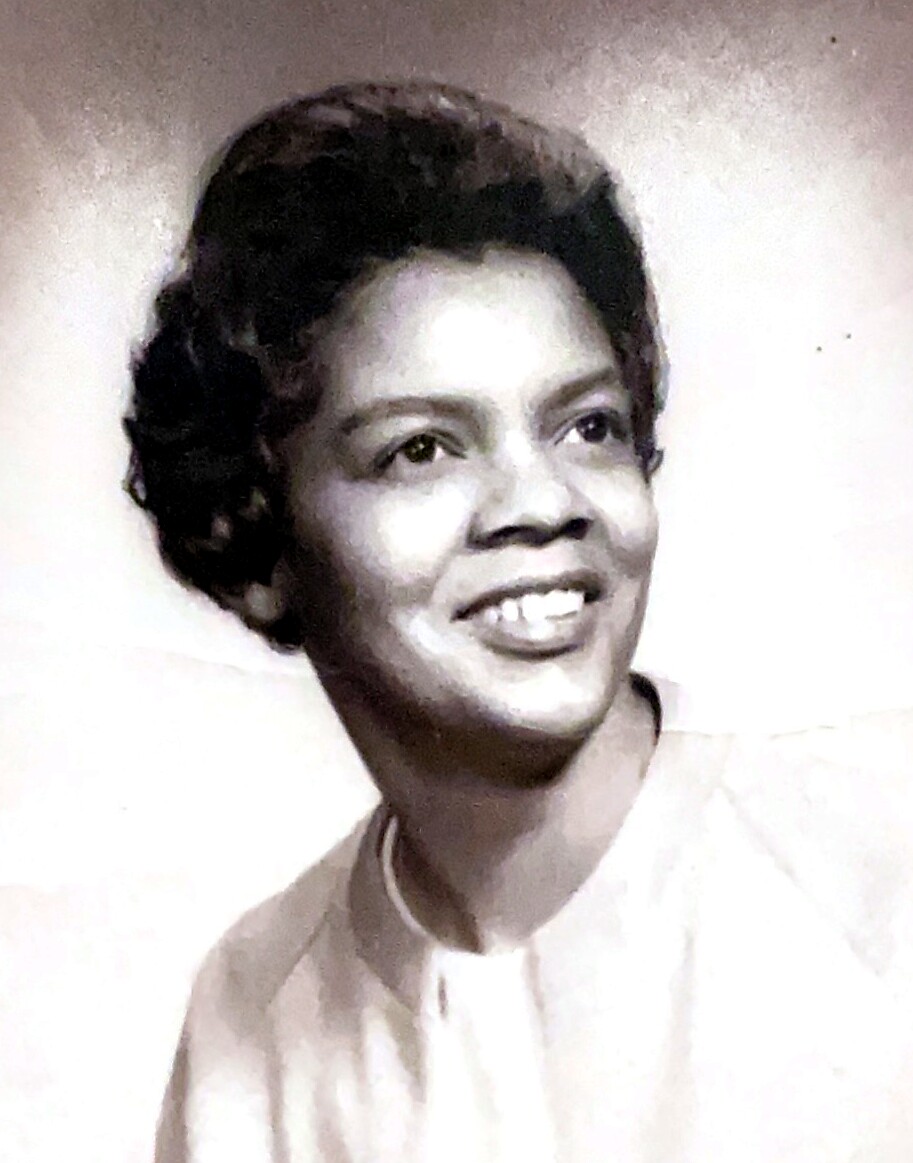 Black-and-white studio portrait of a smiling woman with short hair wearing a light blouse.