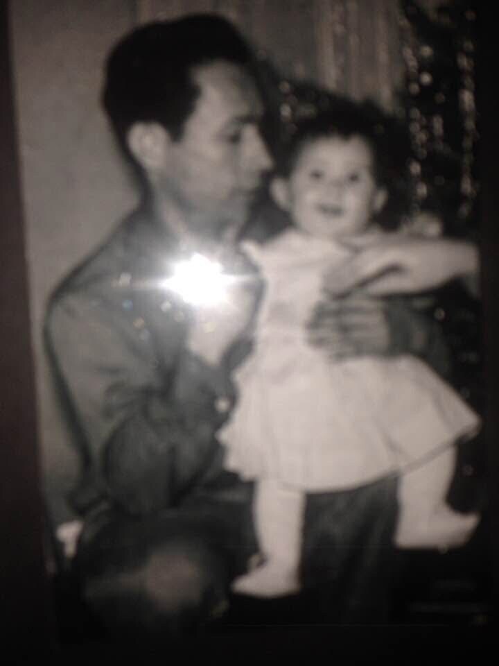 Black-and-white photo of a man holding a smiling young girl in a dress on his lap