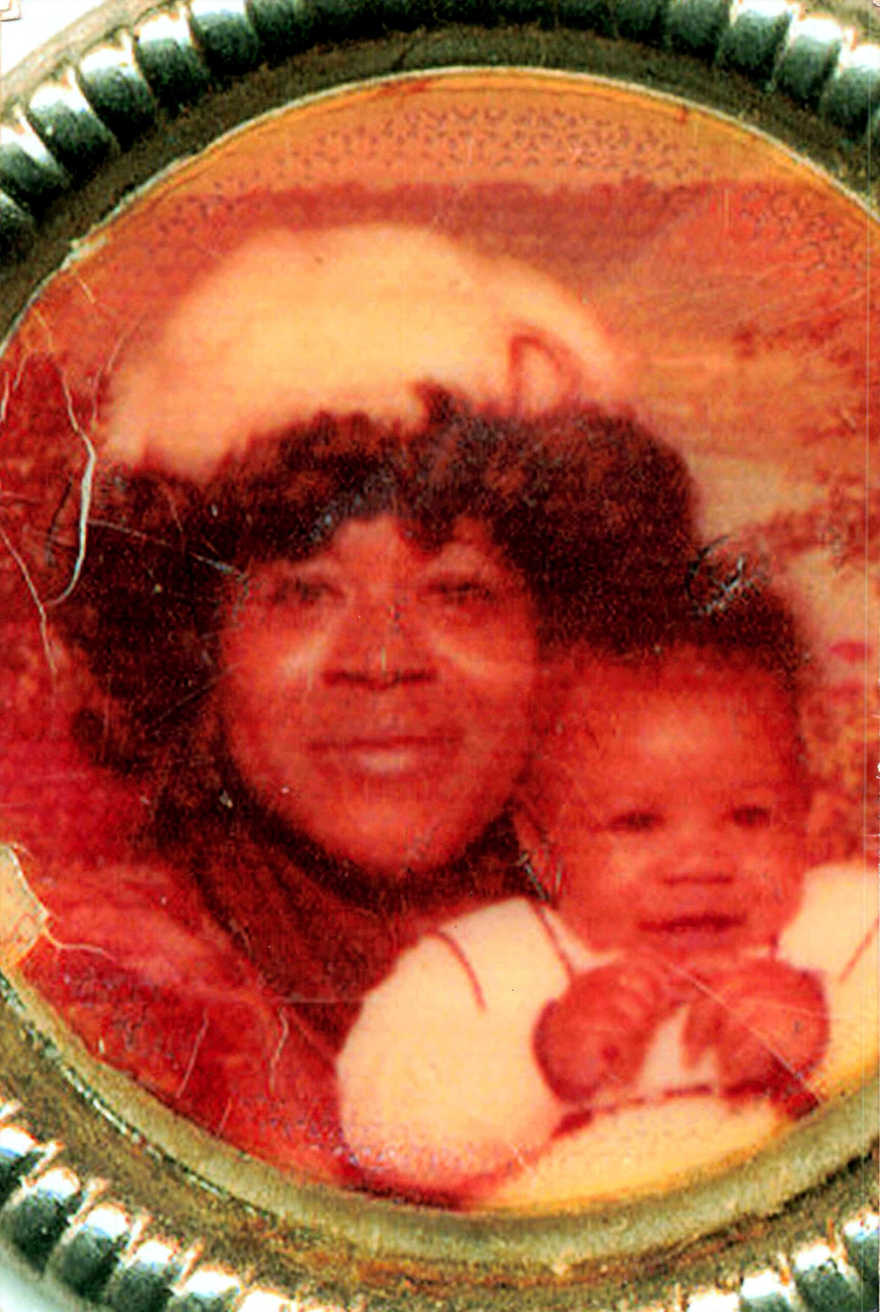 Round brass frame containing a red-tinted vintage photo of a man and a child posing together.
