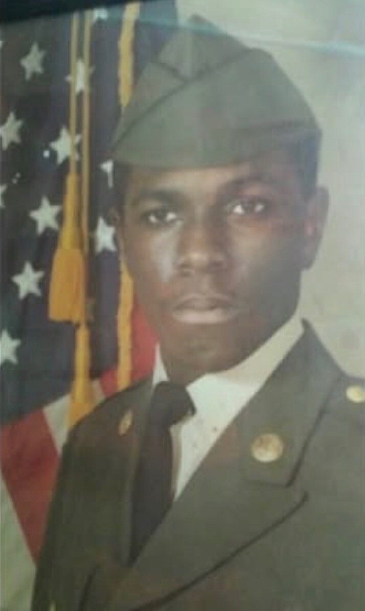 Portrait of a young man in a military dress uniform with an American flag backdrop.
