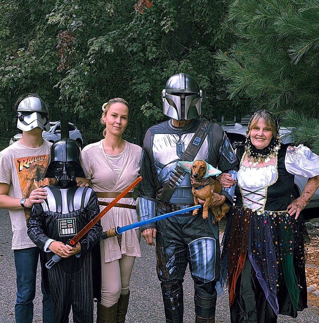 Group of five people in Star Wars costumes posing outdoors with a small dog in a cape.
