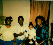 Group photo of five relatives posing in a living room: two women on the ends, a man in the center holding a baby, and a young girl beside him.