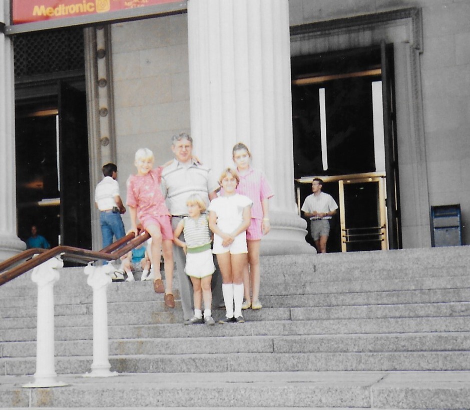 Family of six posing on the steps of a large, columned building (courthouse/mederal building).
