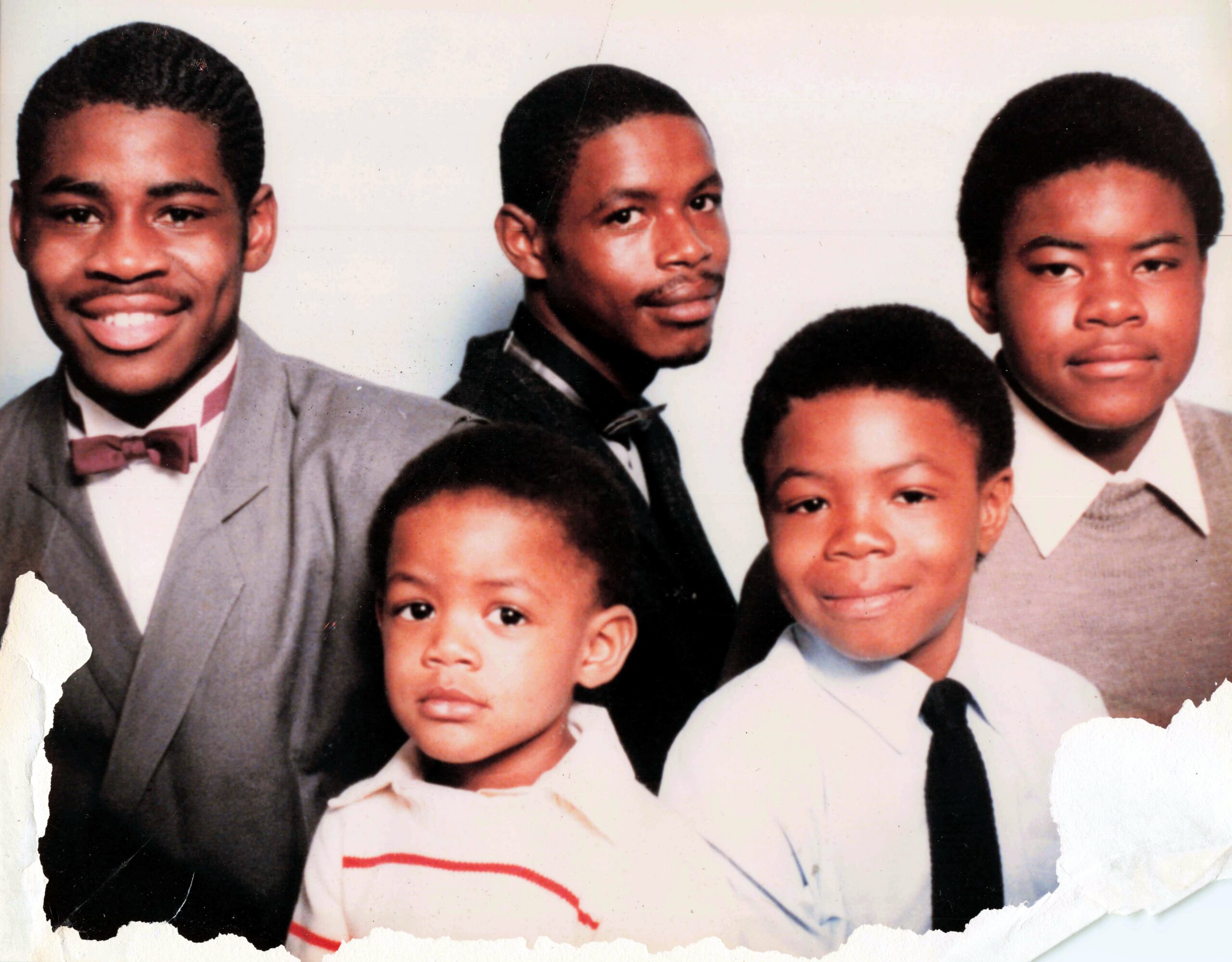 Group portrait of several young men and boys in formal suits posing for a studio photo.