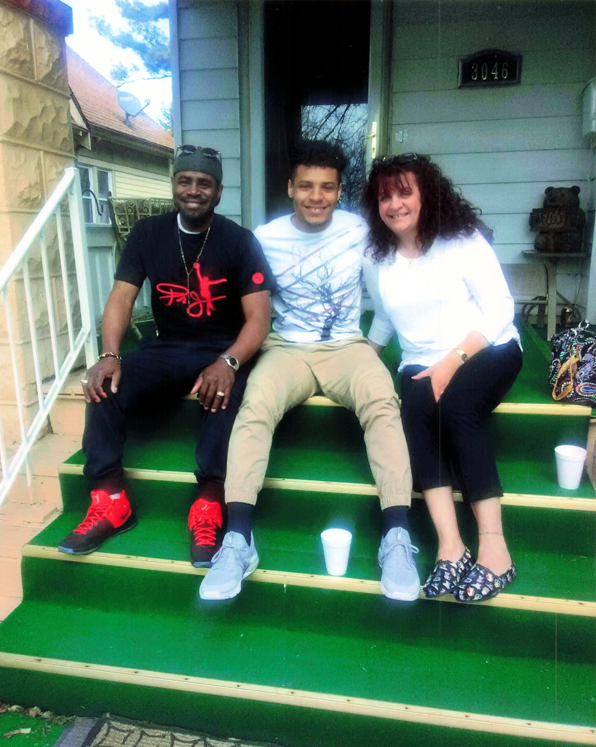 Three friends sit on green front-porch steps, smiling at the camera with house number 3046 in the background.