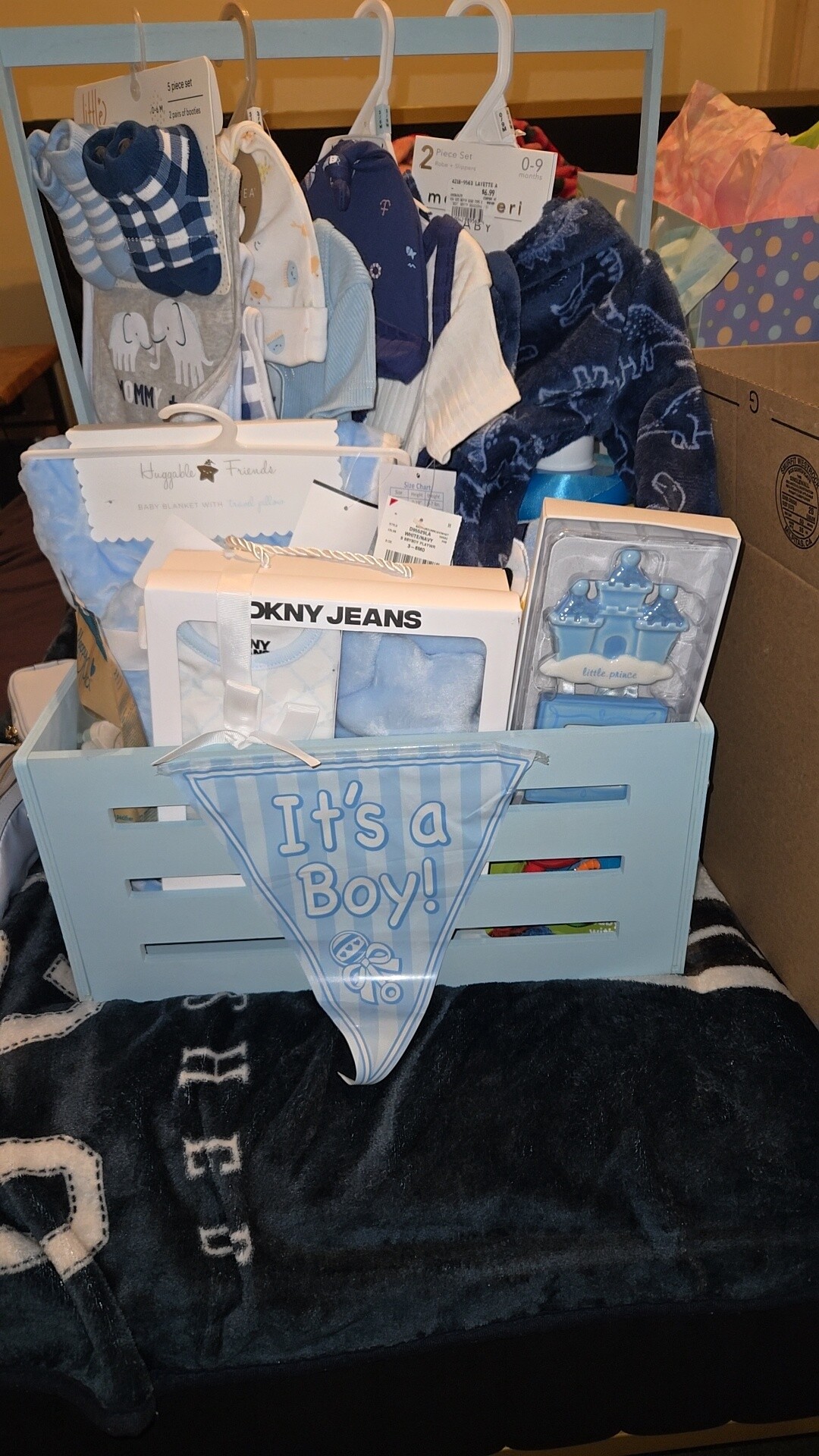 Blue baby gift set with clothing, blankets, and a banner reading 
