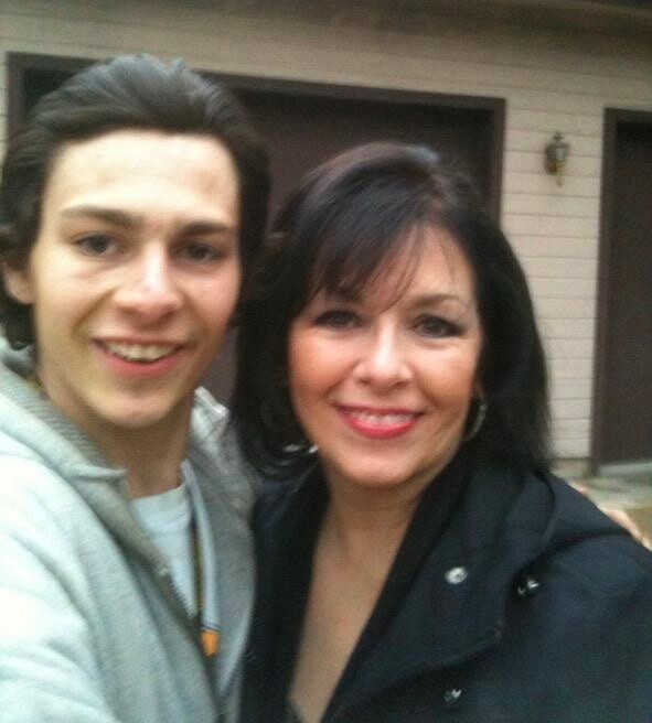 Smiling young man and woman taking a selfie outdoors in front of a house.