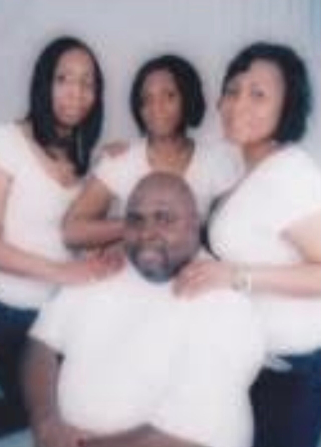 Group of five adults posing for a photo indoors; three women in the back row and two men in front.