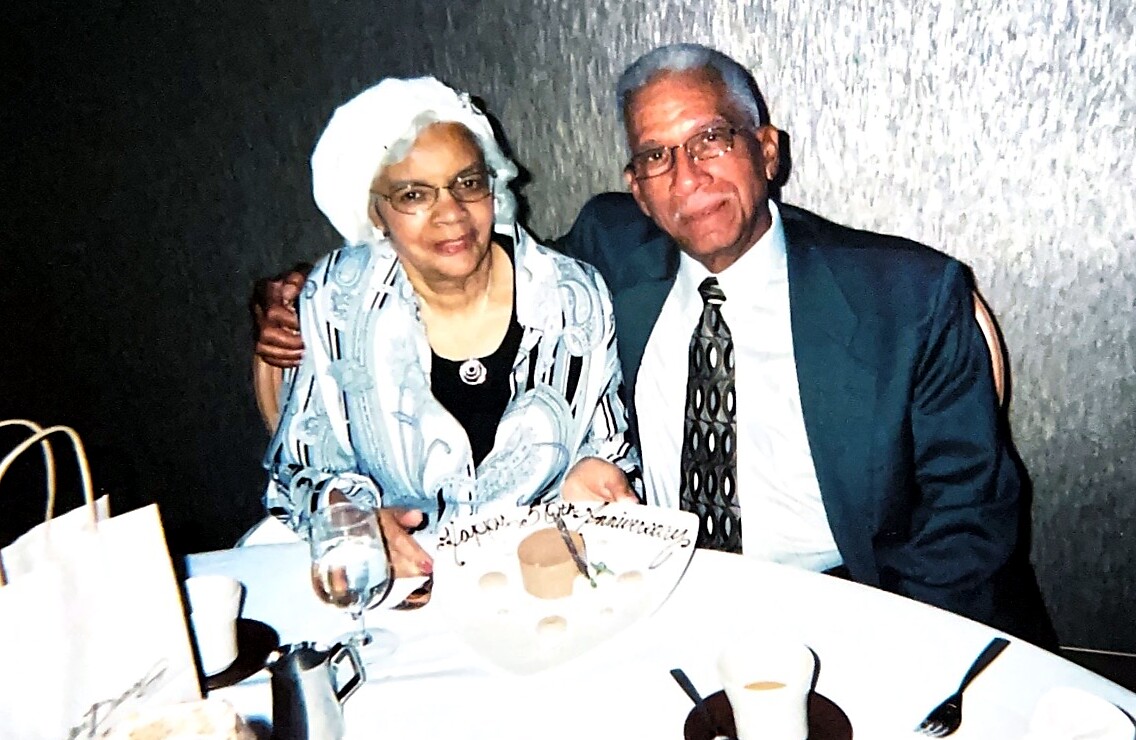Older couple at a restaurant table, smiling, with a dessert plate showing a 'Happy Birthday' message.