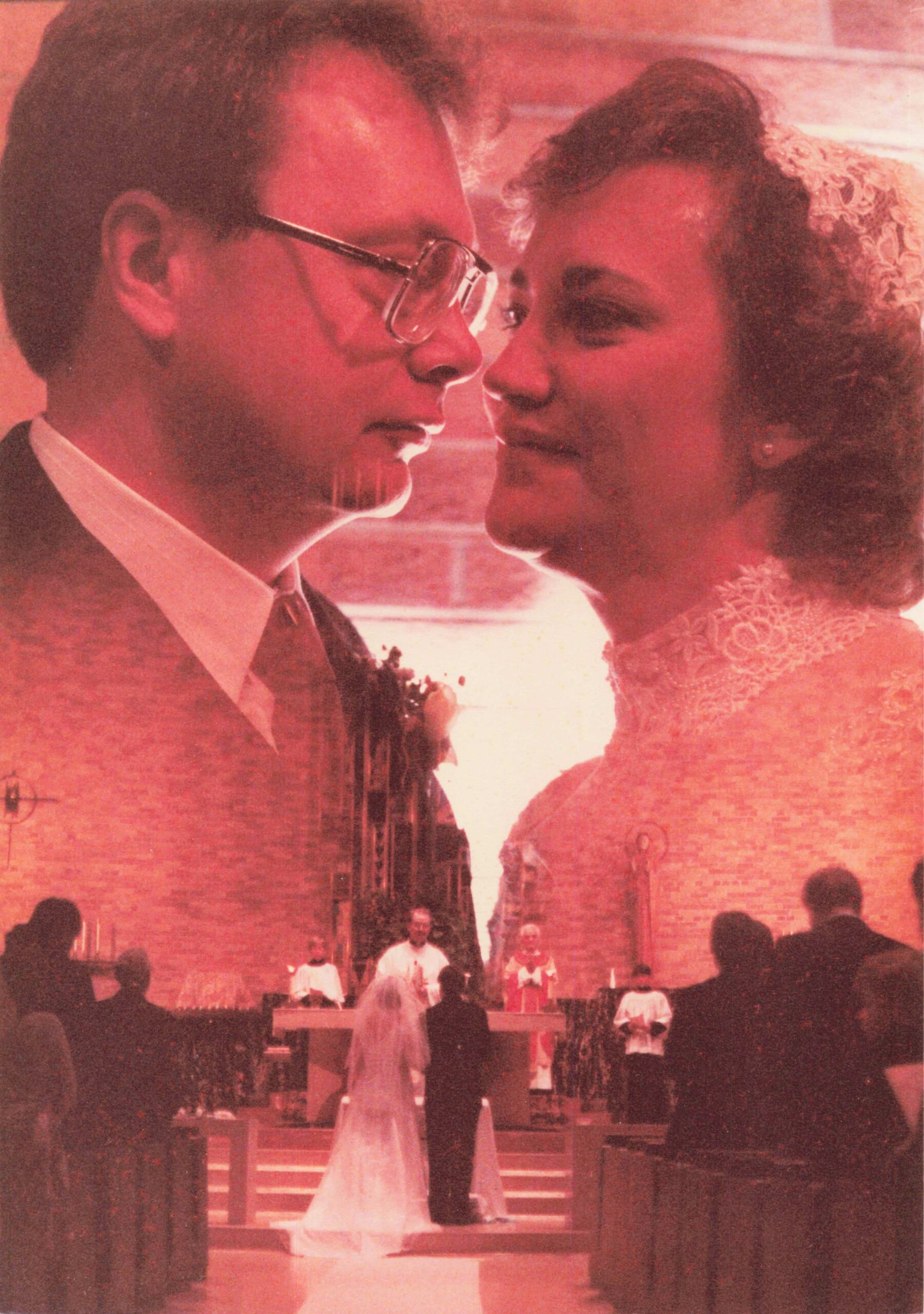 Close-up of a bride and groom about to kiss at their wedding ceremony, with guests in the background.