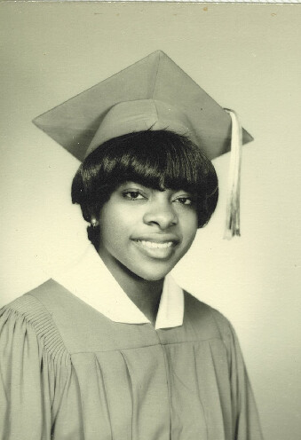 Black-and-white graduation portrait of a smiling young woman in cap and gown.
