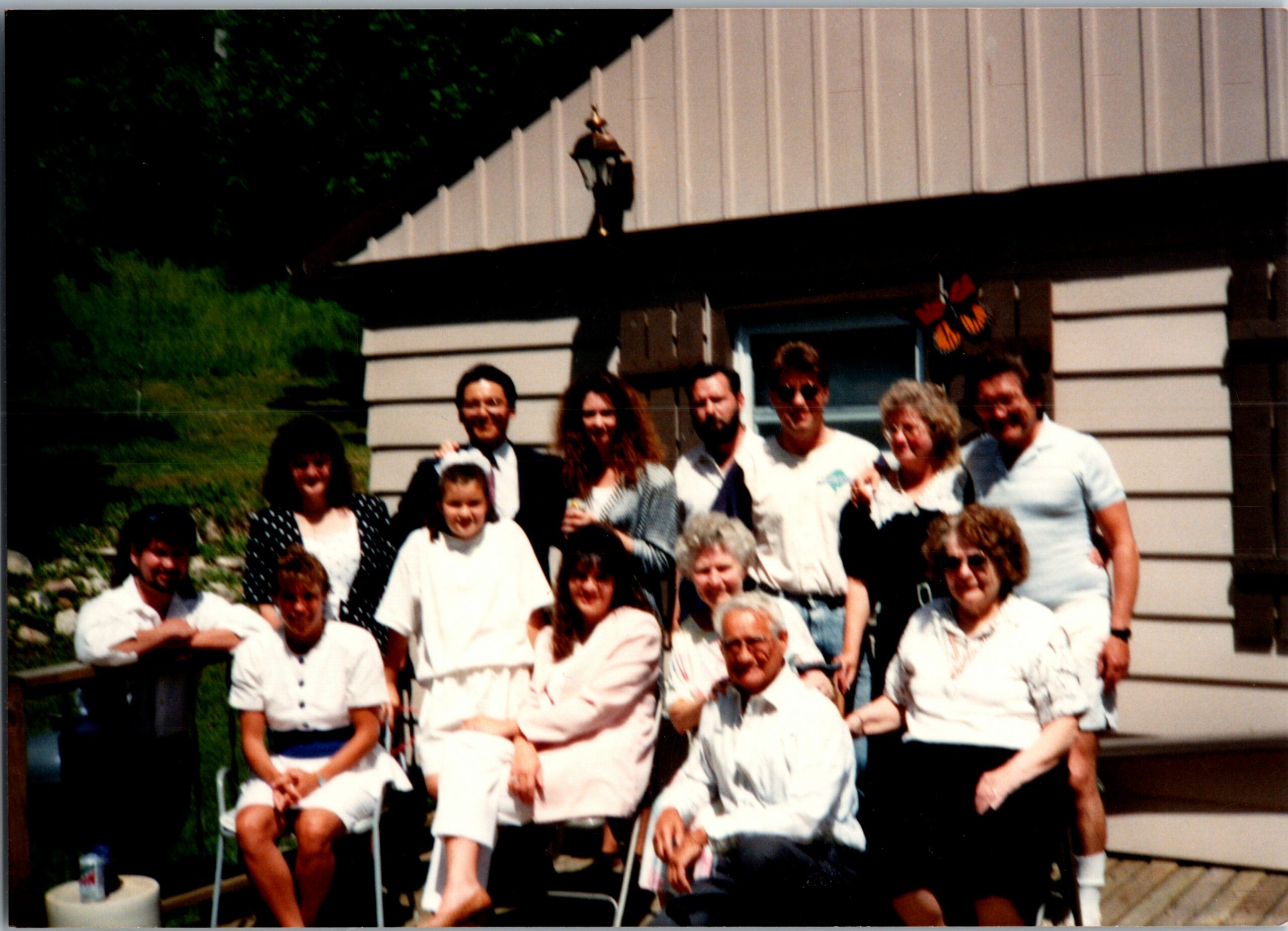 Group of people posing together outdoors in front of a beige building with butterfly decor on the wall.