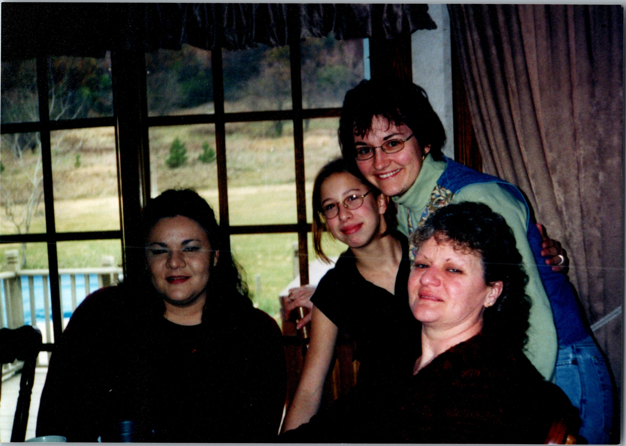 Group of people posing for a casual indoor photo near a large window, smiling at the camera.
