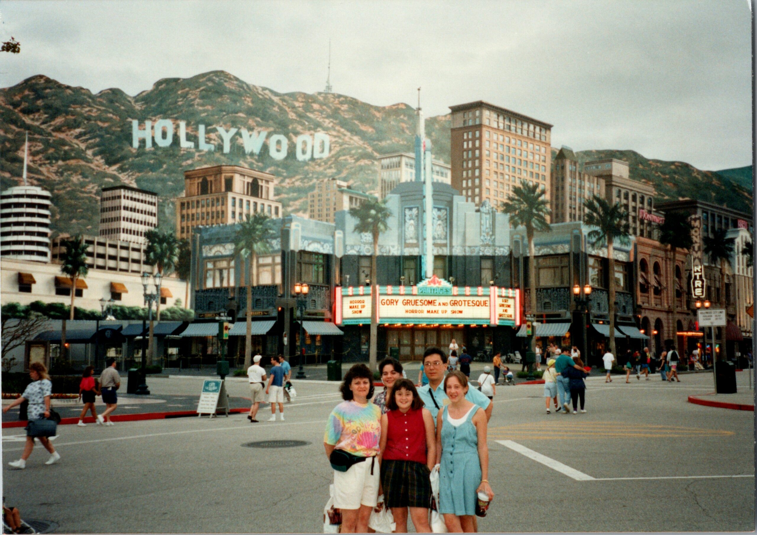 Group of friends posing for a photo on Hollywood Boulevard, with the famous hills and sign in the background.