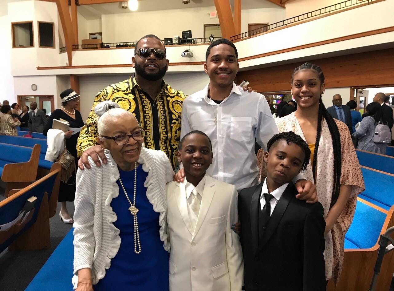 Smiling multigenerational family posing in a church sanctuary, dressed in formal attire.