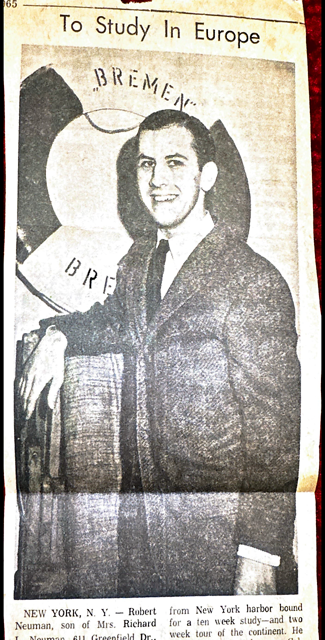 Young man in a suit shaking hands in front of a ship image in a newspaper clipping with the headline 'To Study In Europe'
