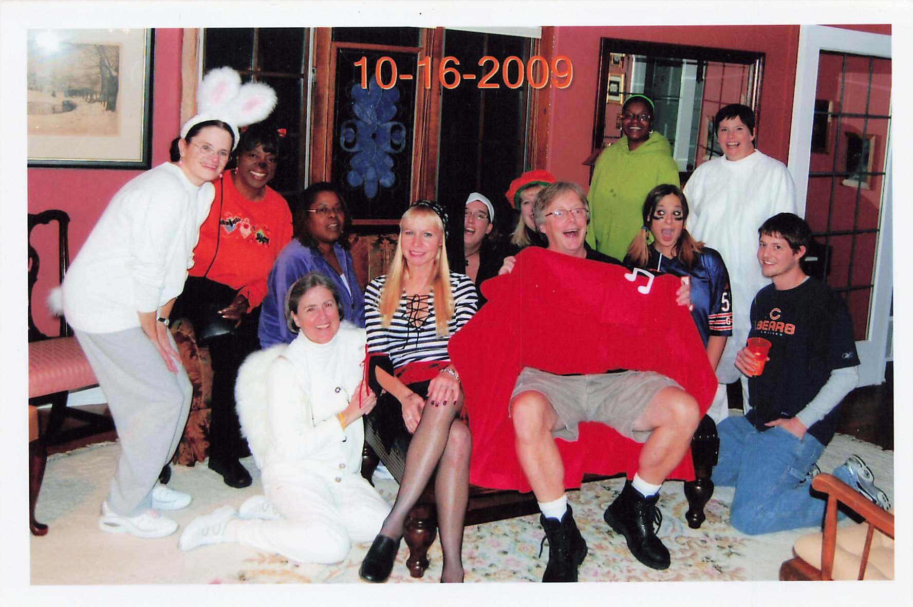 Group of friends at a costume party posing indoors, some wearing bunny ears and angel wings, dated 10-16-2009.