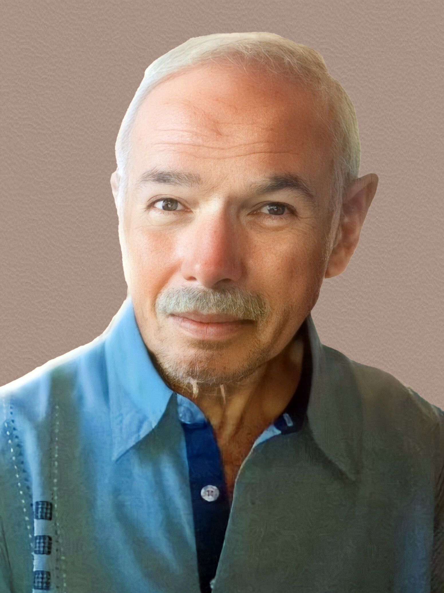 Close-up portrait of an older man with white hair and mustache, wearing a blue shirt, facing the camera.