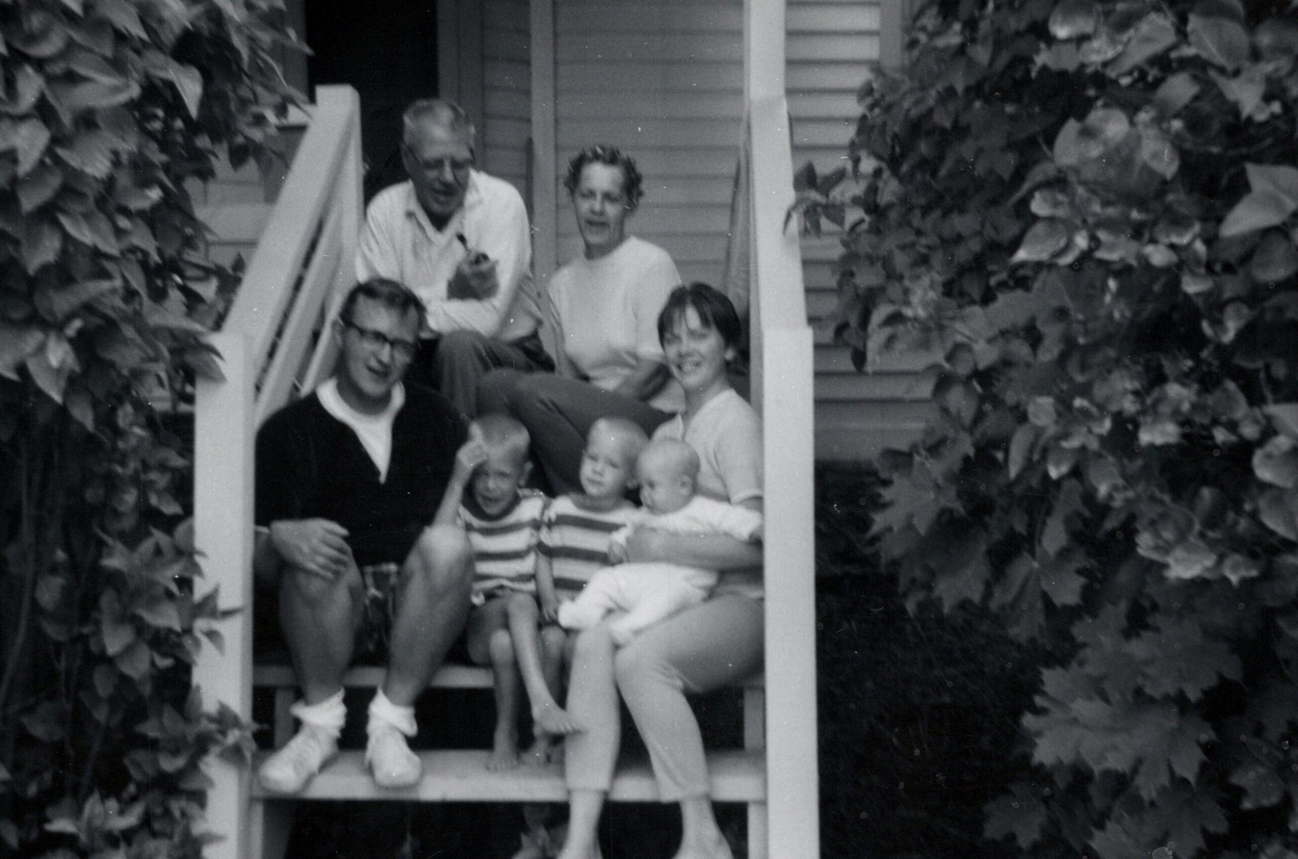 Family group on the front porch steps, surrounded by ivy, posing for the photo.