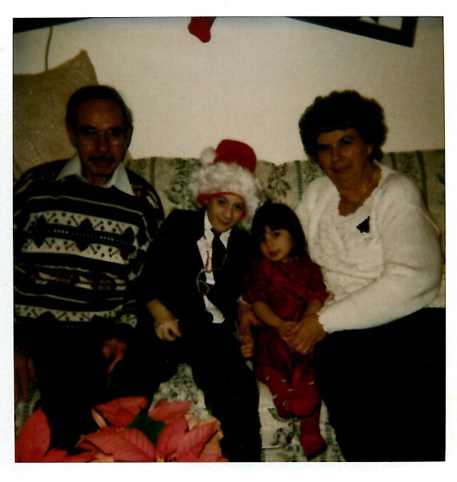 Family of four posing on a sofa for a Christmas photo; child in a Santa hat sits between an older man and a woman on either side.