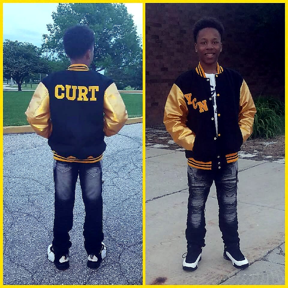 Back view of a person wearing a black-and-gold varsity jacket with 'CURT' on the back, standing in a park.