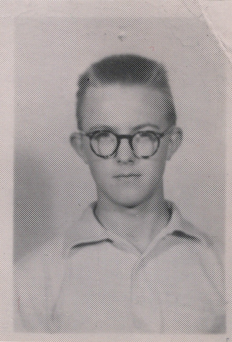 Black-and-white portrait of a young man with short hair and round glasses, facing the camera.