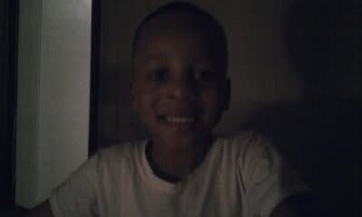 Child smiling at the camera in a dimly lit room.