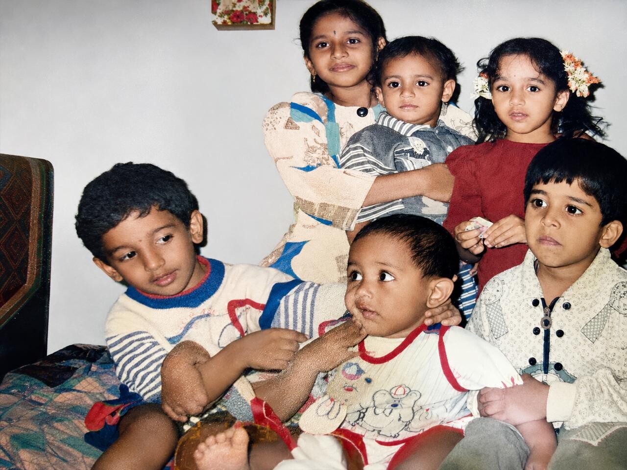 Group of six children posing together on a couch in a living room for a family photo.